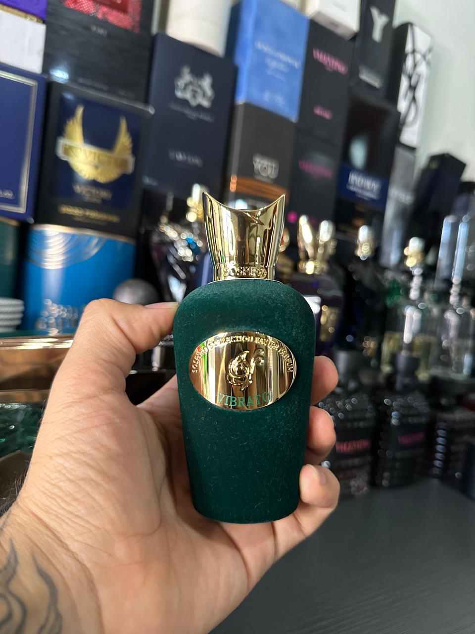 Frasco verde de perfume sostenido en la mano